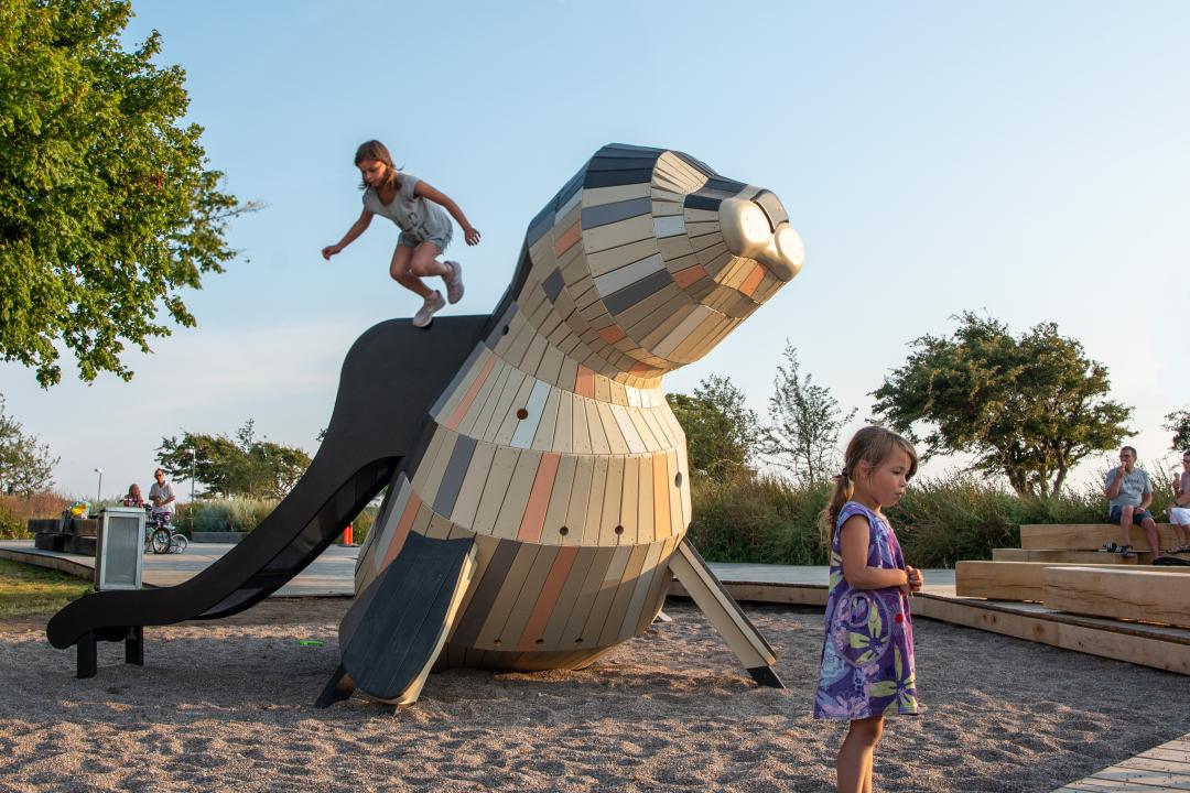 Girl jumping from slide on seal play structure at MONSTRUM playground