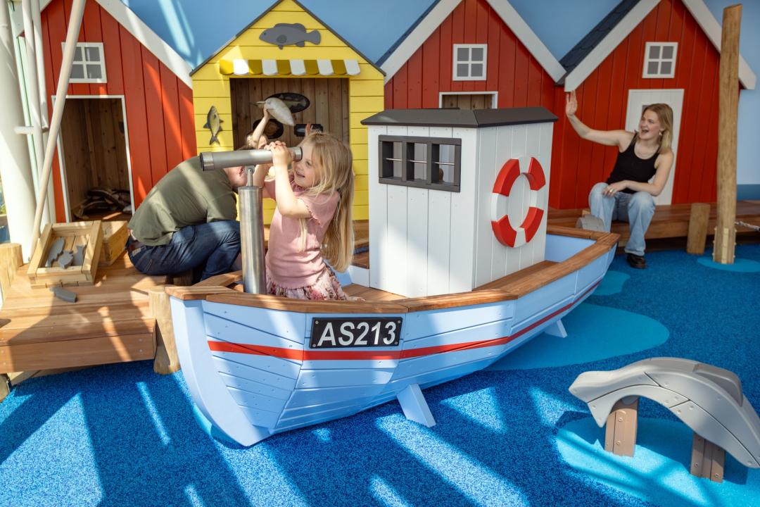 Girl playing on wooden fishing boat at indoor maritime playground