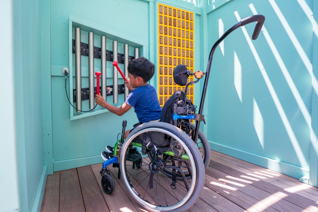 Boy playing on musical play feature at inclusive playground