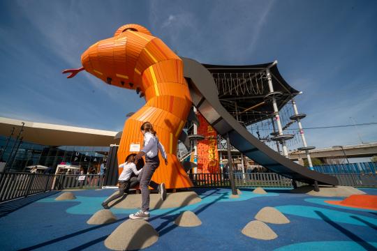 Children playing at big orange wooden dragon playground structure