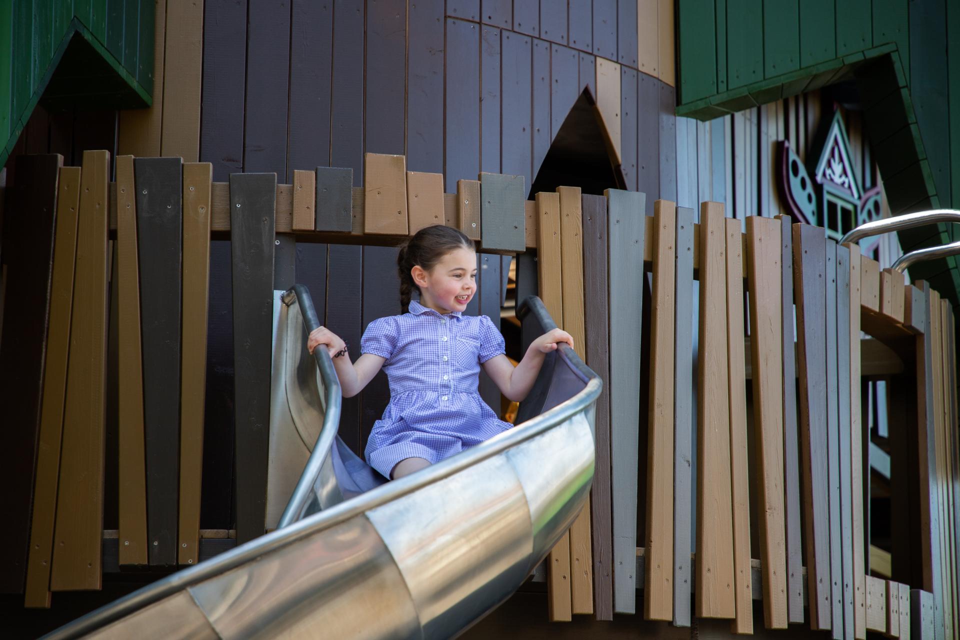 A girl sliding down slide at Lilidorei