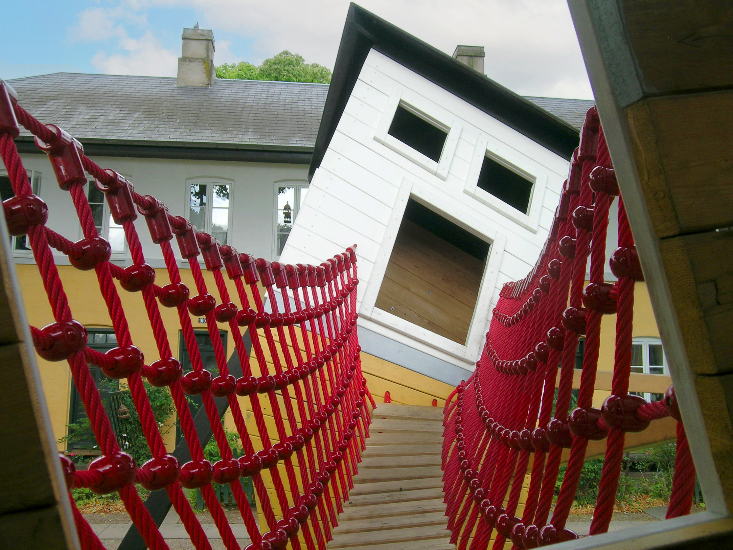 A wobbly suspension bridge at The Crooked House playground by MONSTRUM Playgrounds