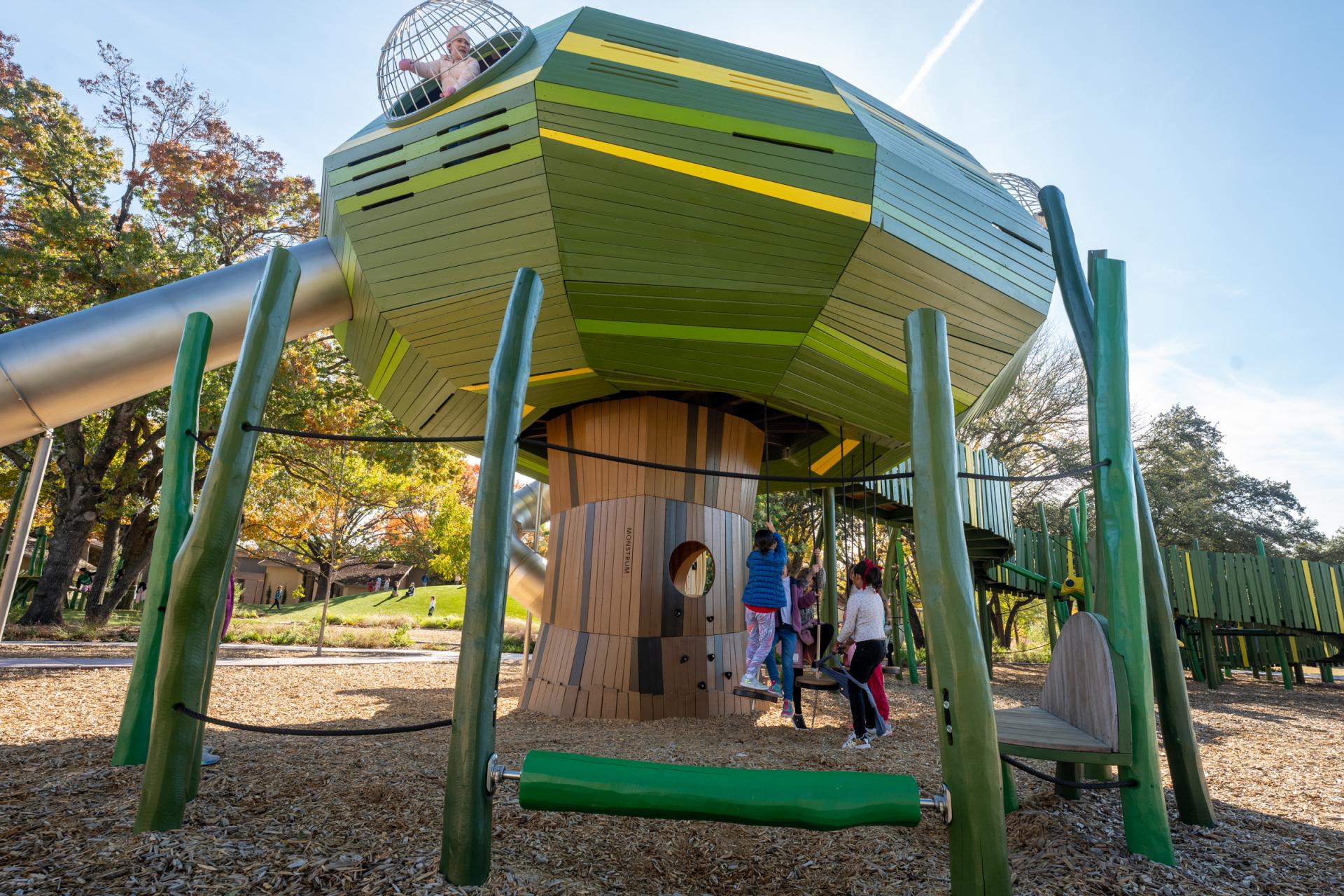 Kids playing on huge wooden tree playground structure