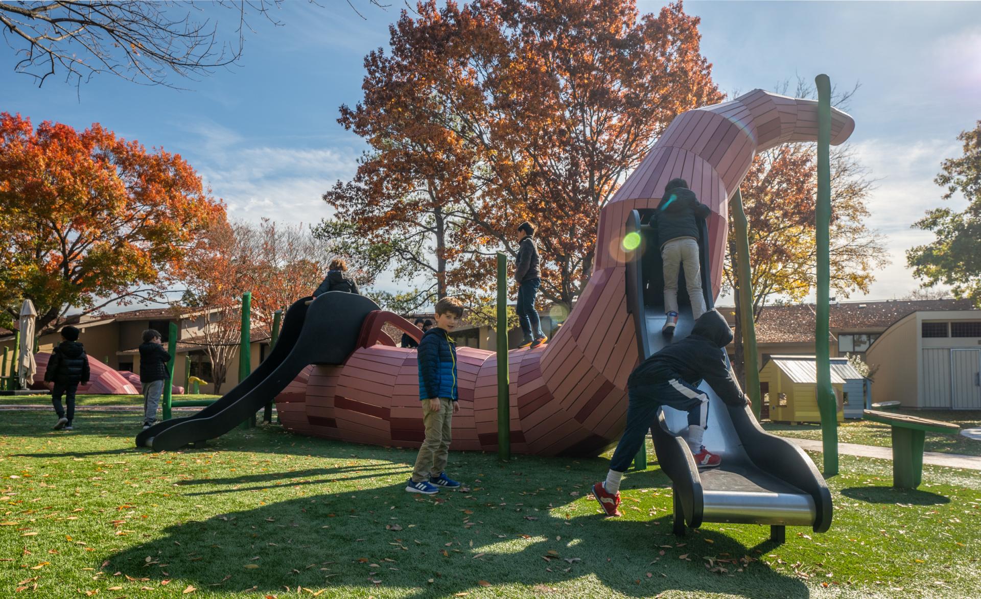 Kids playing on huge worm structure at playground