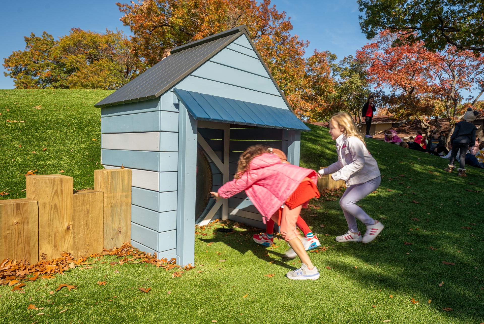 Kids running into tunnel through hillside at playground