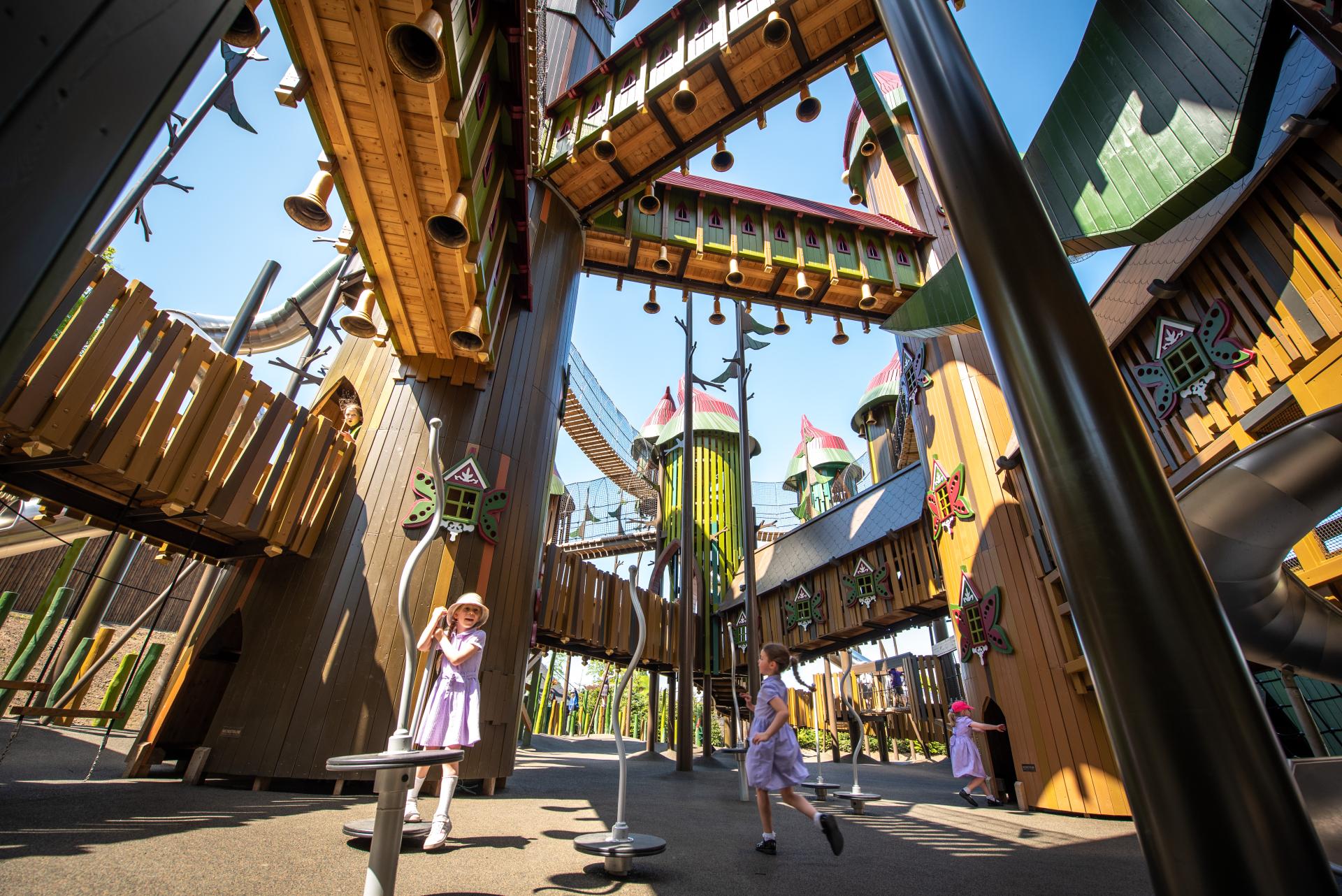 Kids playing at Lilidorei playground surrounding by huge towers and bridges