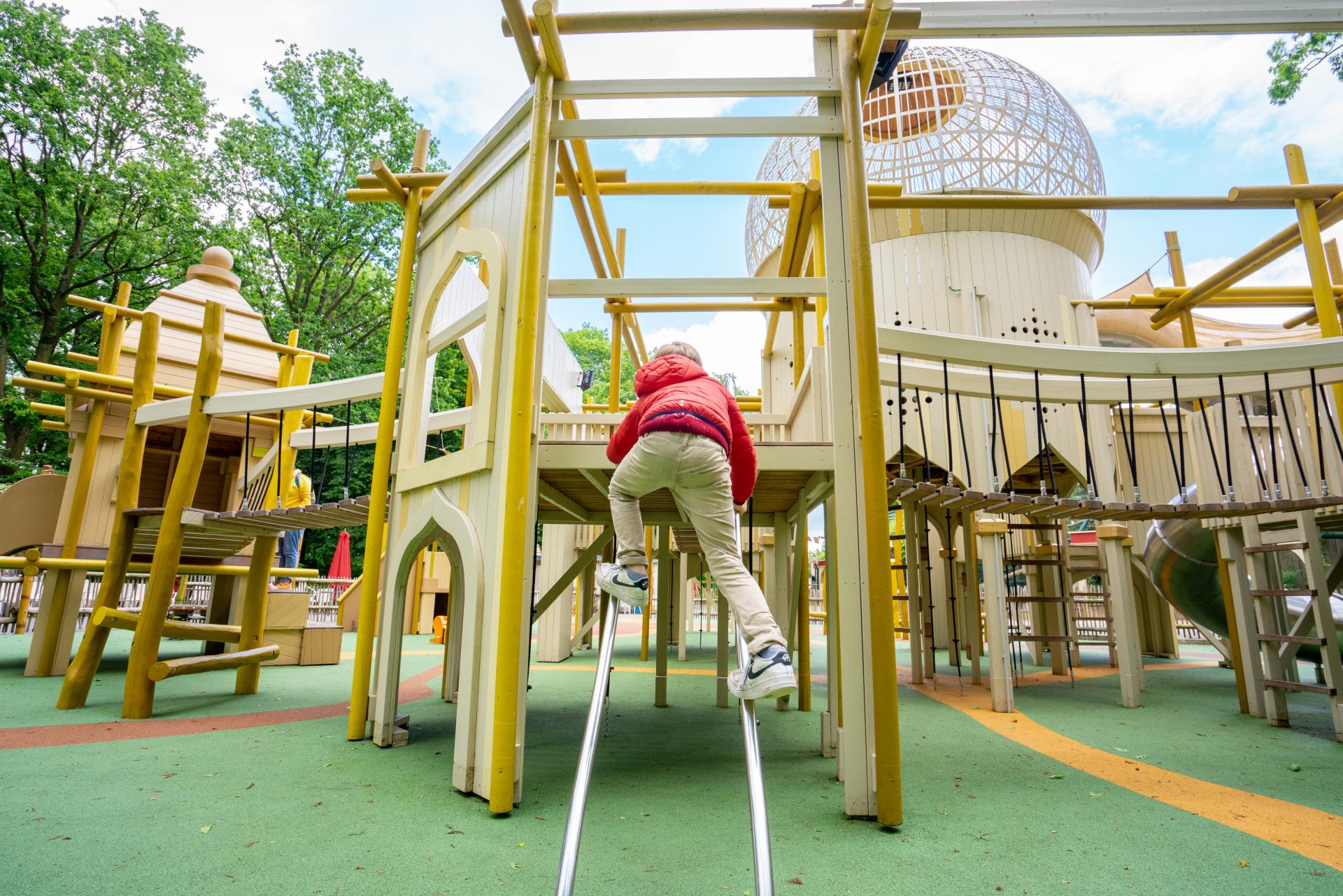 Boy climbing up metal poles at playground