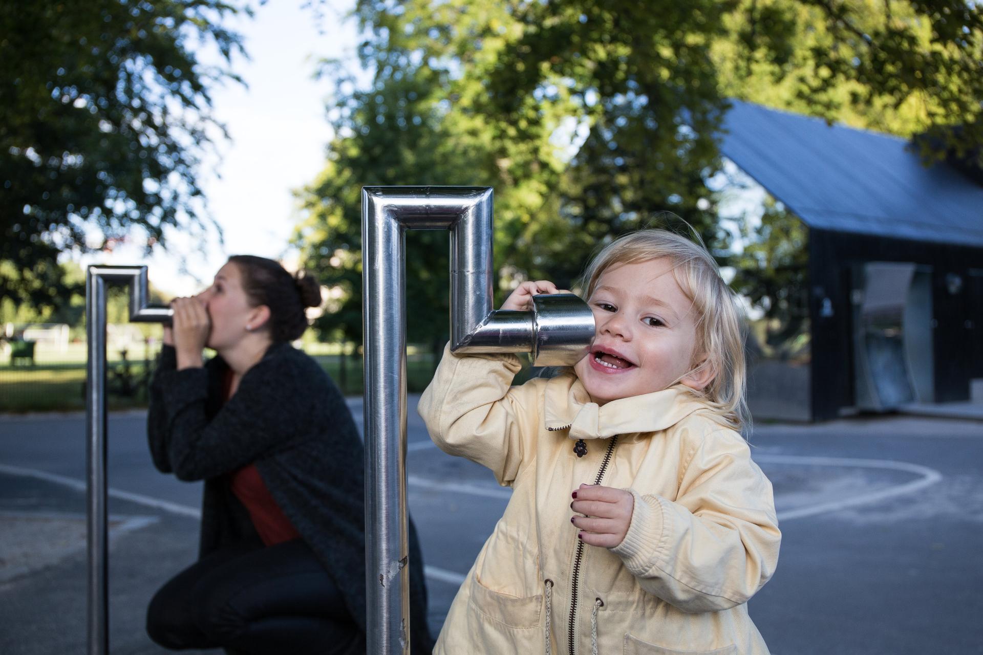 Girl and her mum talking on tube phones at playground