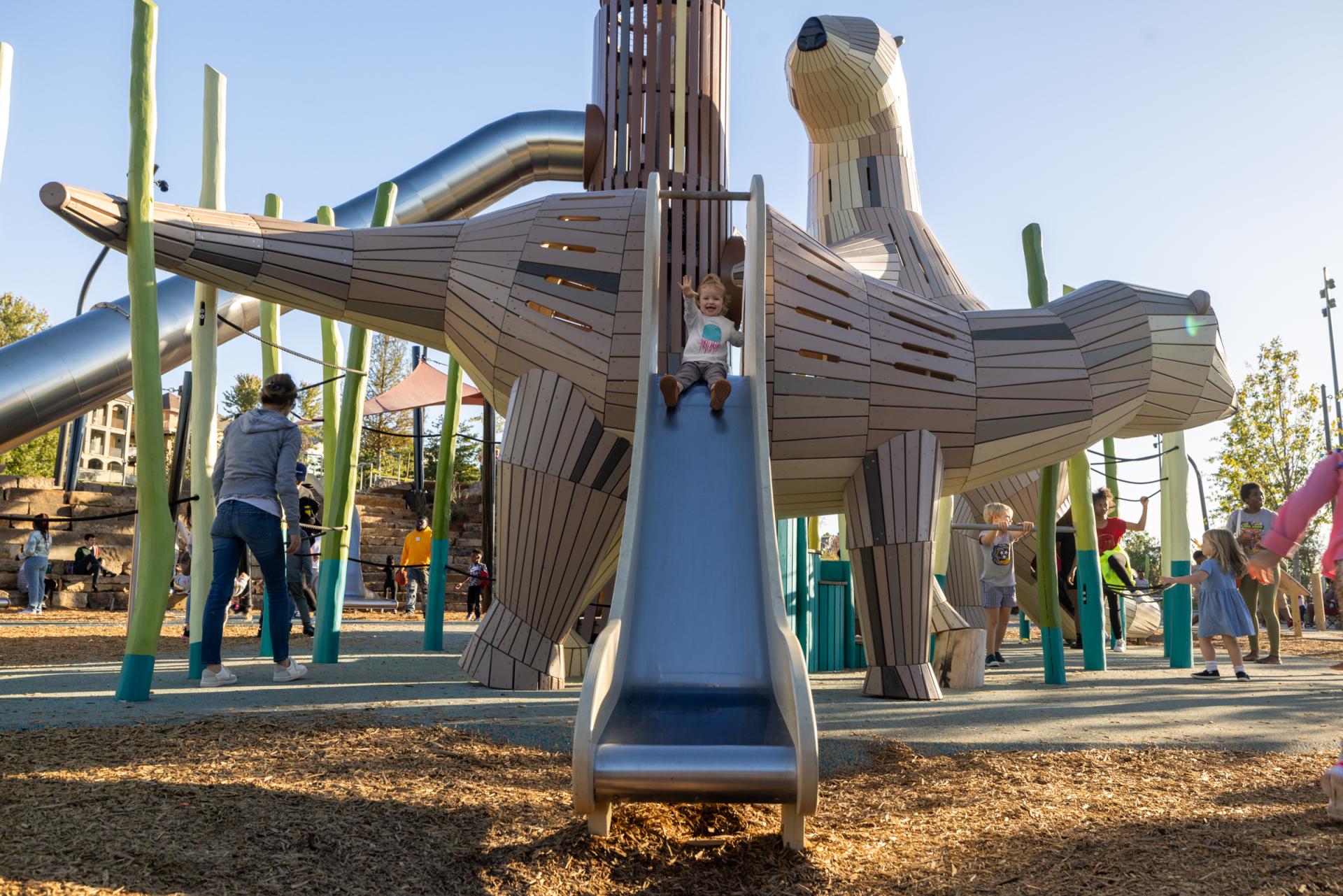 Girl sliding down slide from baby otter playground structure