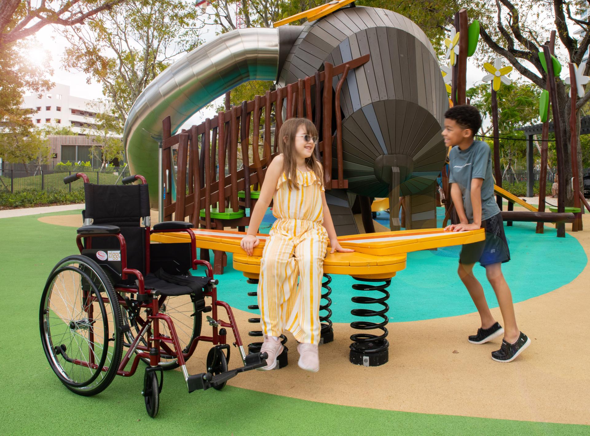 Girl in wheelchair with her friend at playground