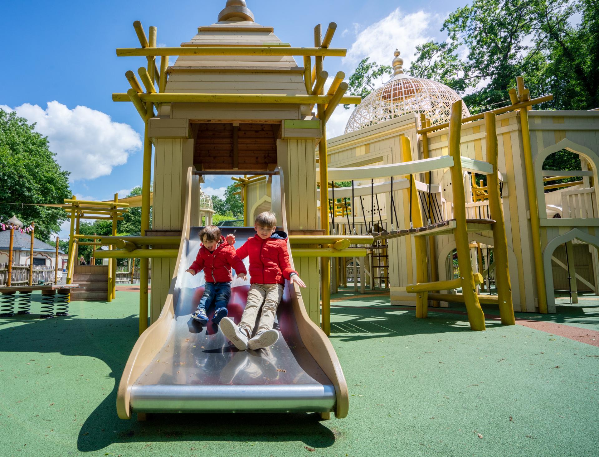 Kids having fun sliding down temple-themed playground slide