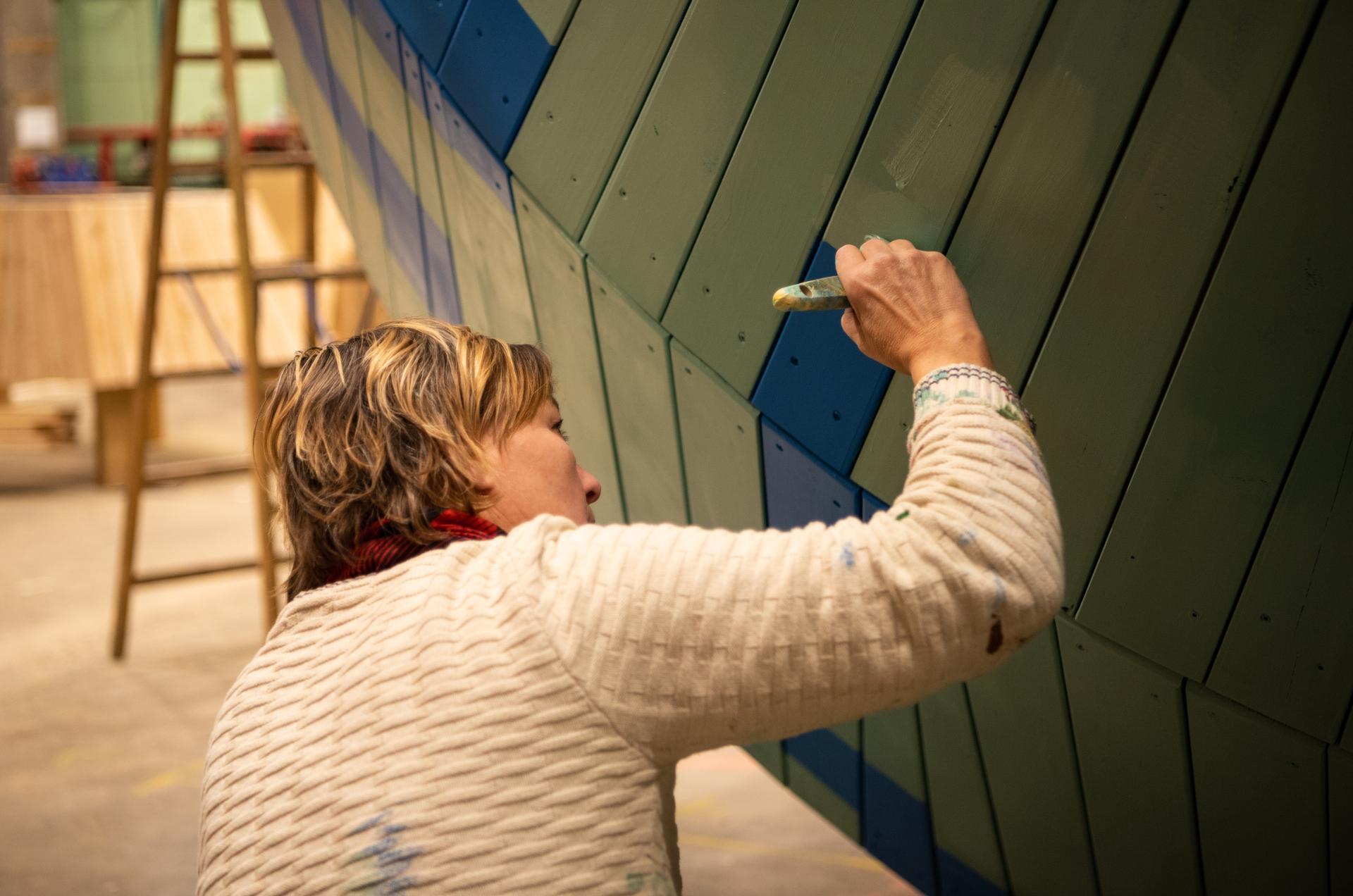 Painter painting playground structure with paintbrush