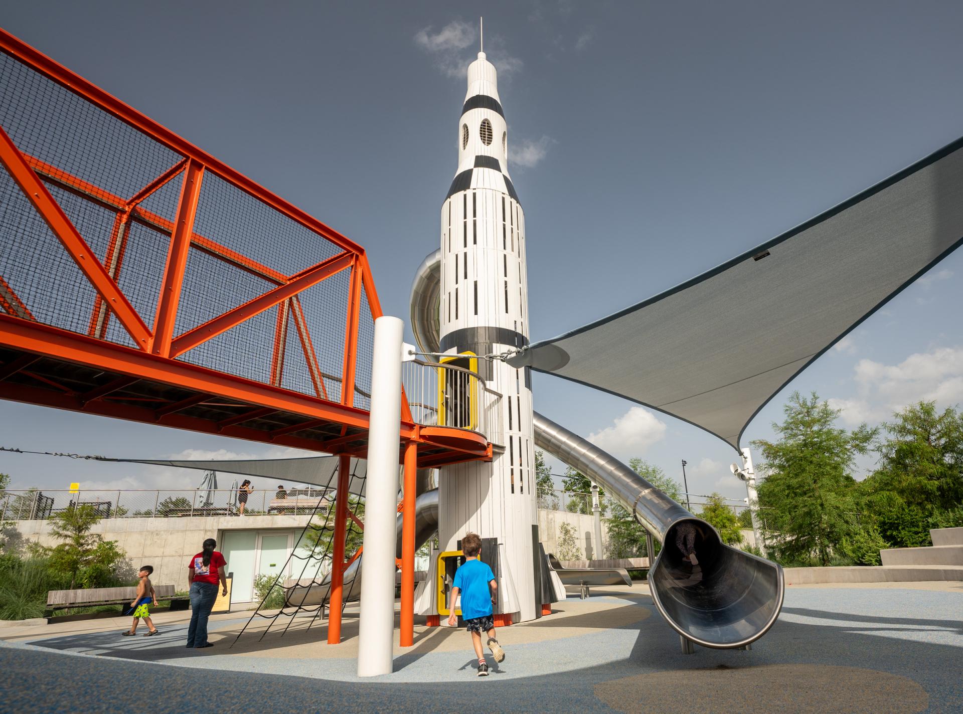 Boy playing at base of huge wooden rocket ship playground structure