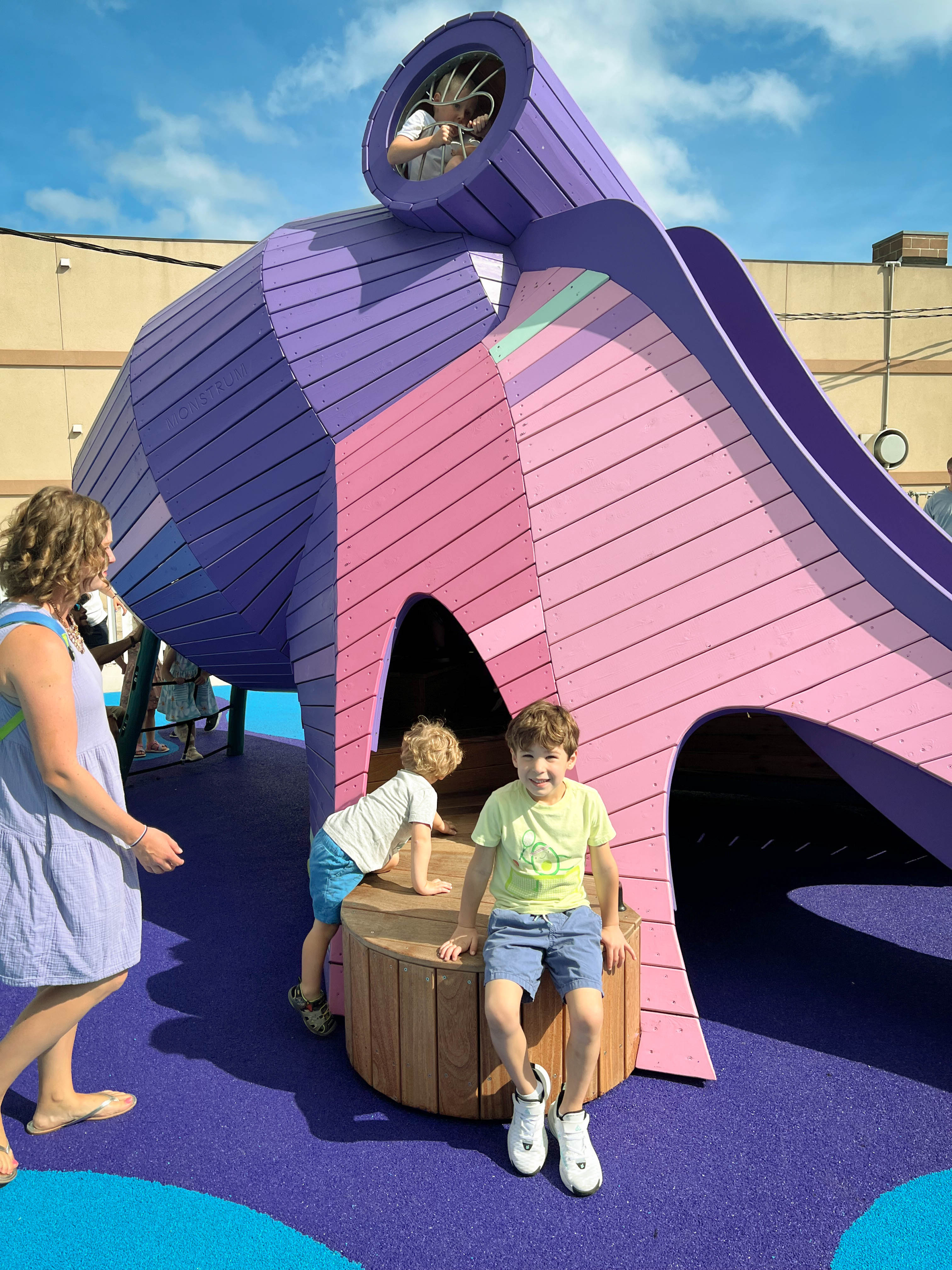 Child sitting on accessible transfer platform to octopus playground feature