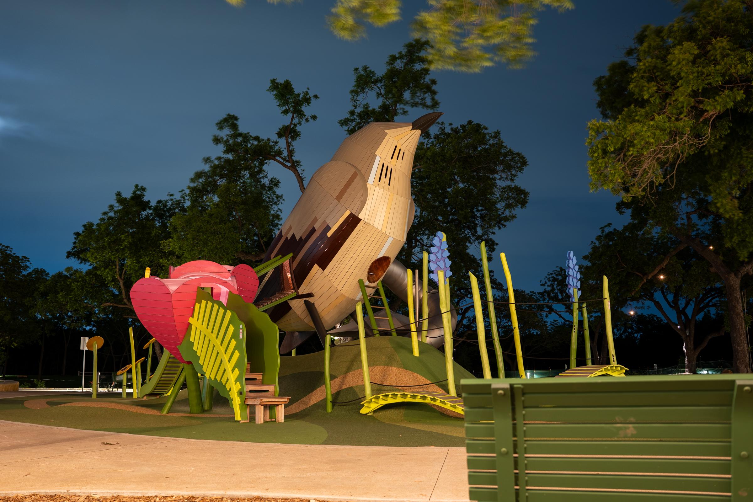 Mockingbird wooden playground structure lit up at night time