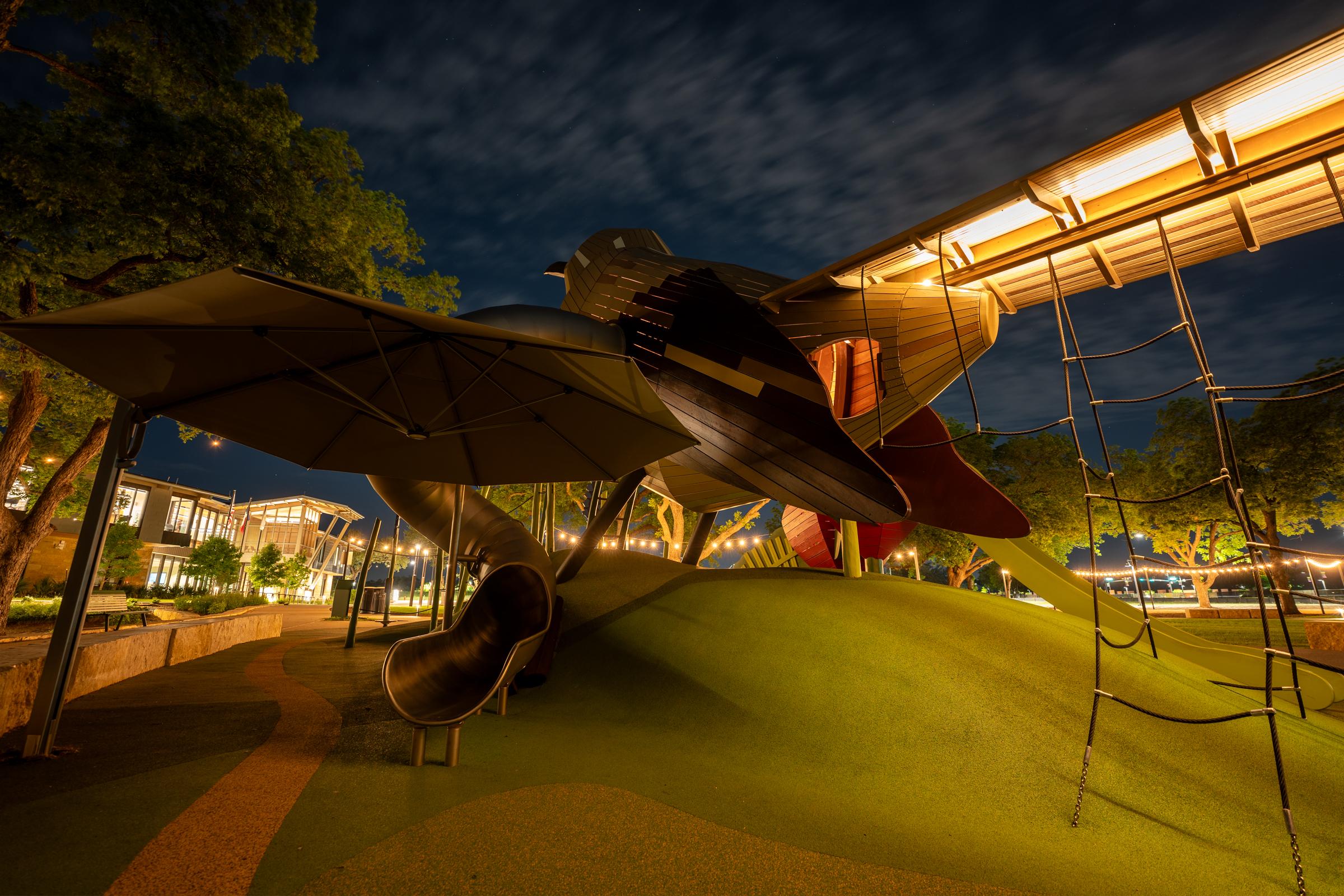 Mockingbird wooden playground structure lit up at night time