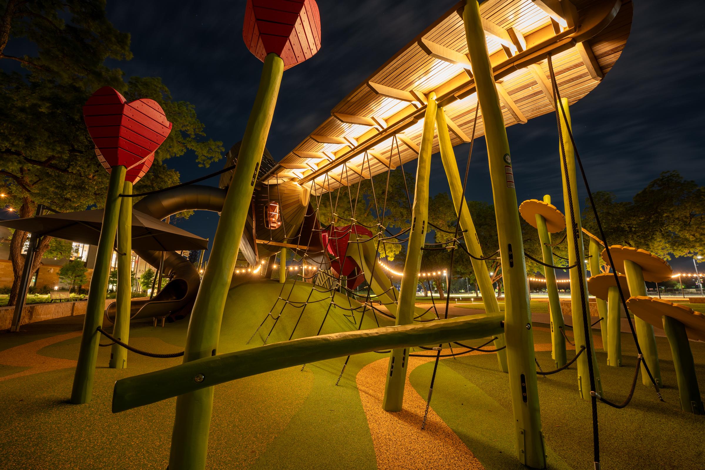 Mockingbird wooden playground structure lit up at night time