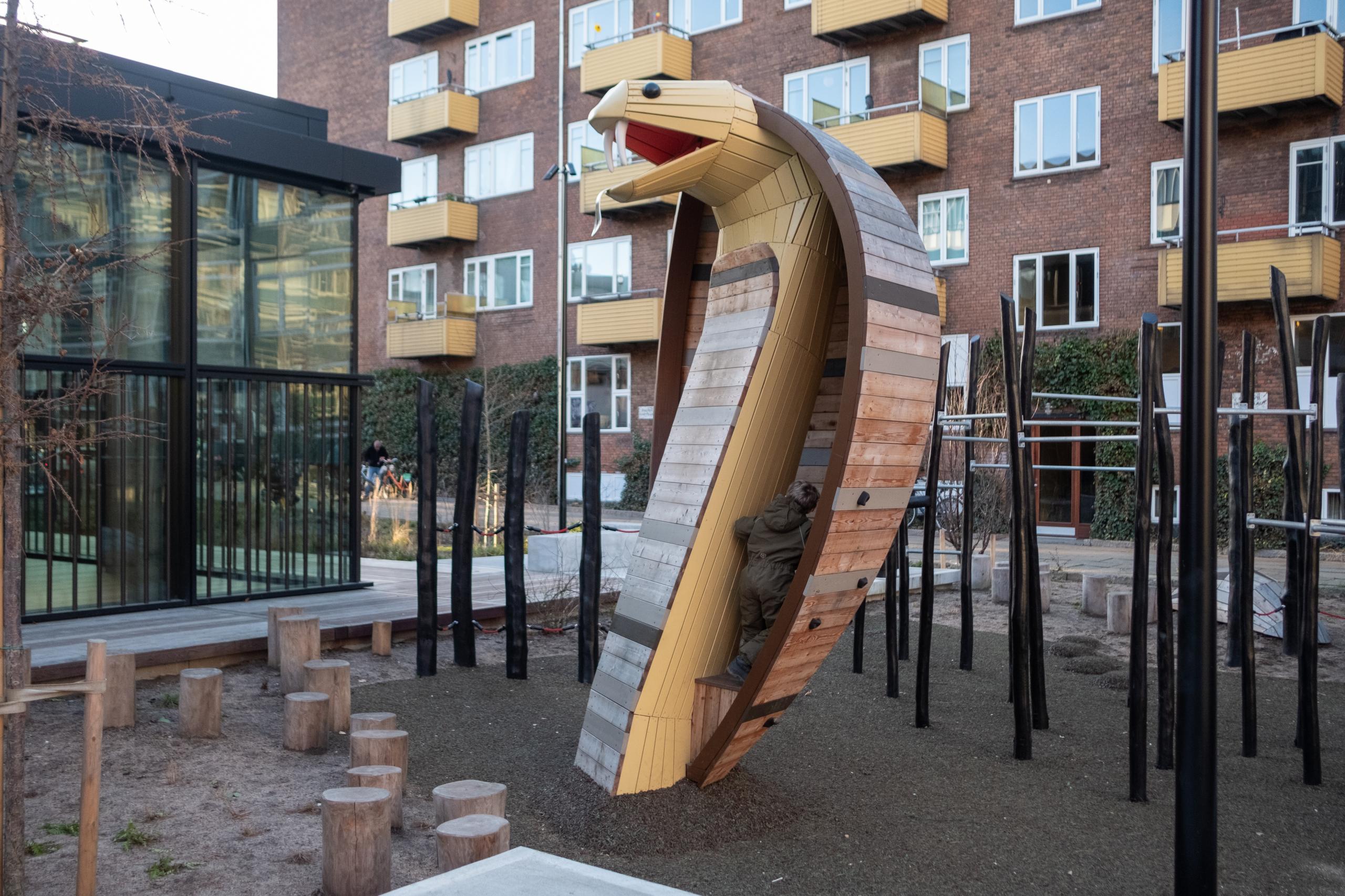 Boy climbing up onto snake playground sculpture