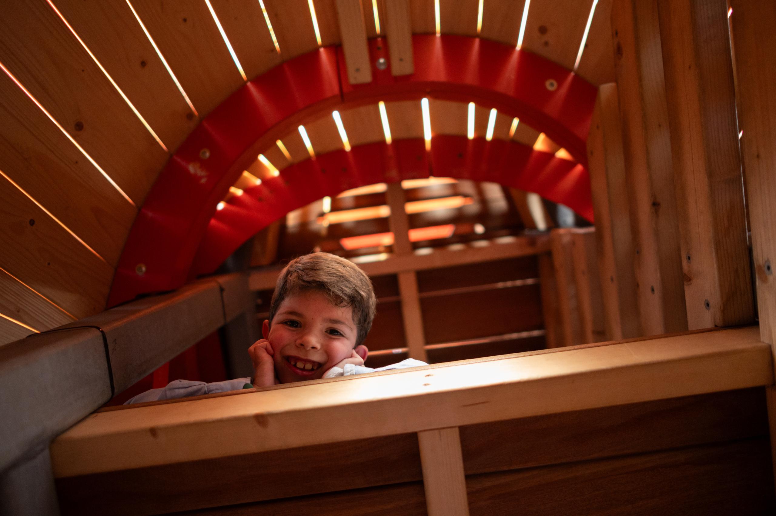 Boy looking down smiling from inside wooden playground structure
