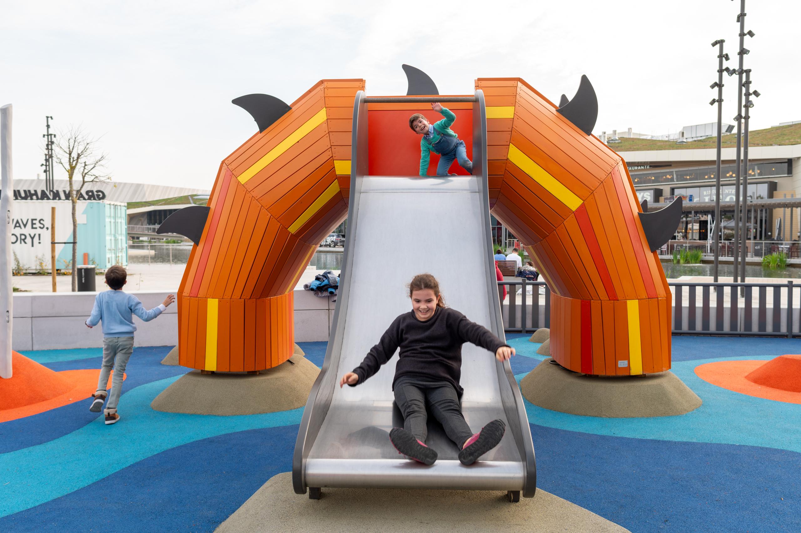 Children smiling and laughing as they slide down colourful playground slide