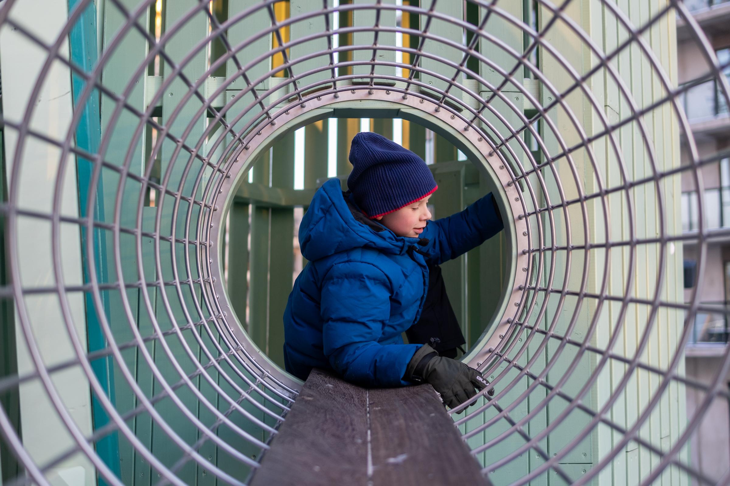 Boy crawling through playground tunnel