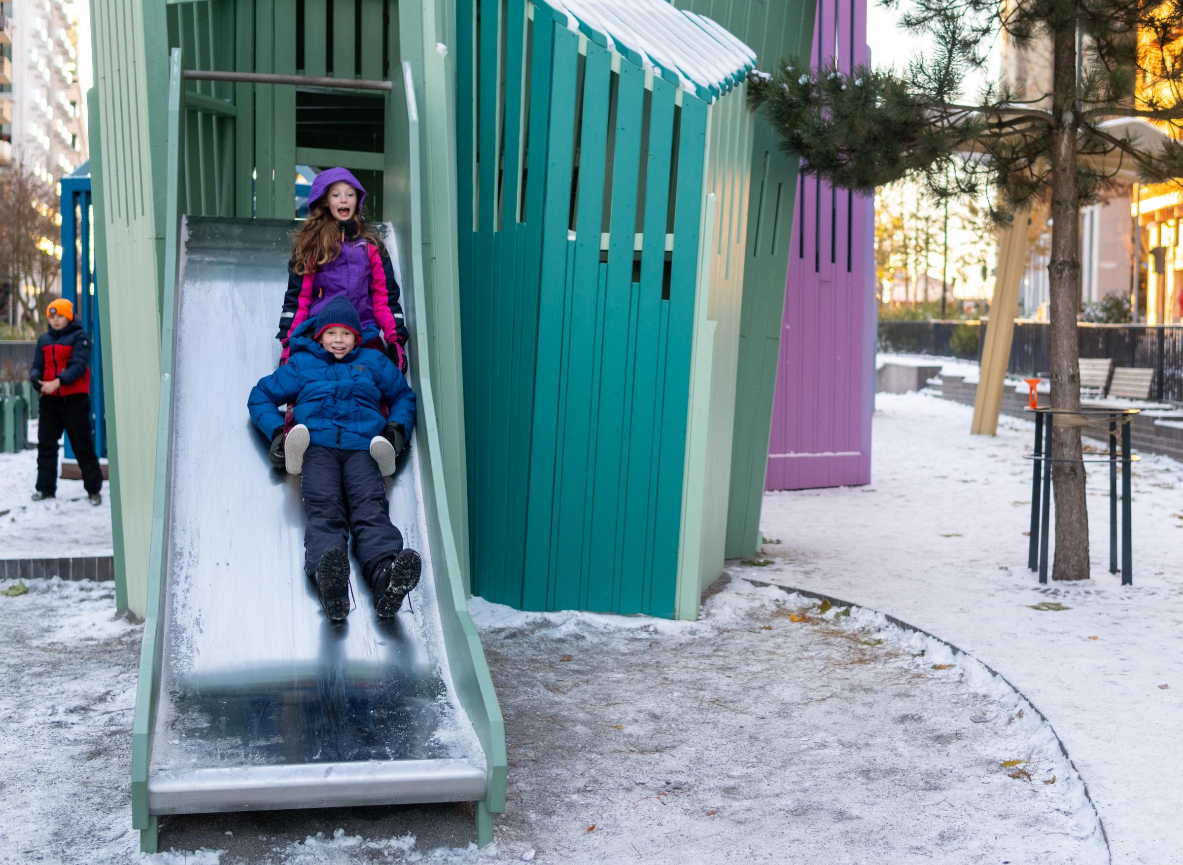Kids laughing as they slide down playground slide together