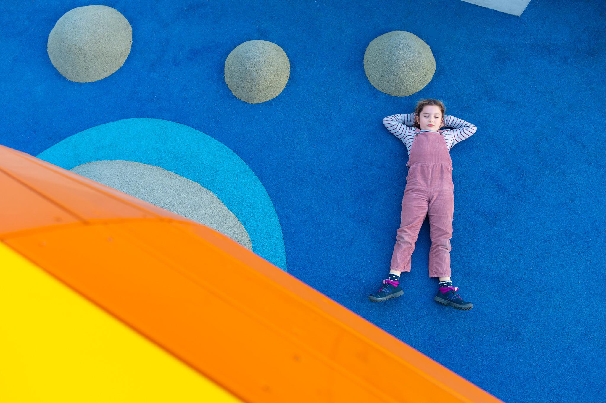 Girl lying on colourful rubber flooring at playground