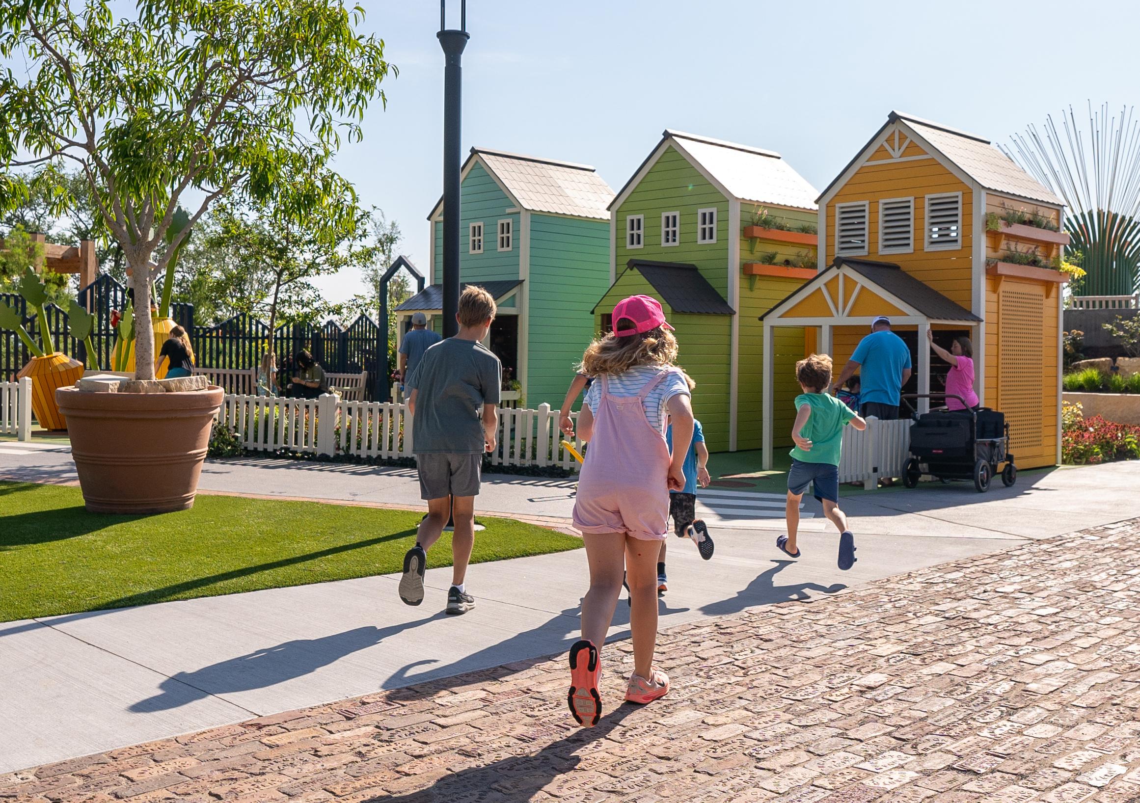 Children running towards wooden playground houses