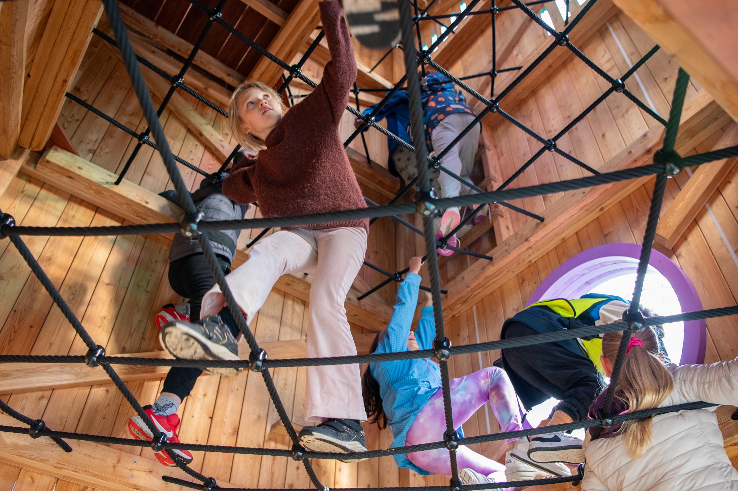 Kids climbing up on rope net in playground towers