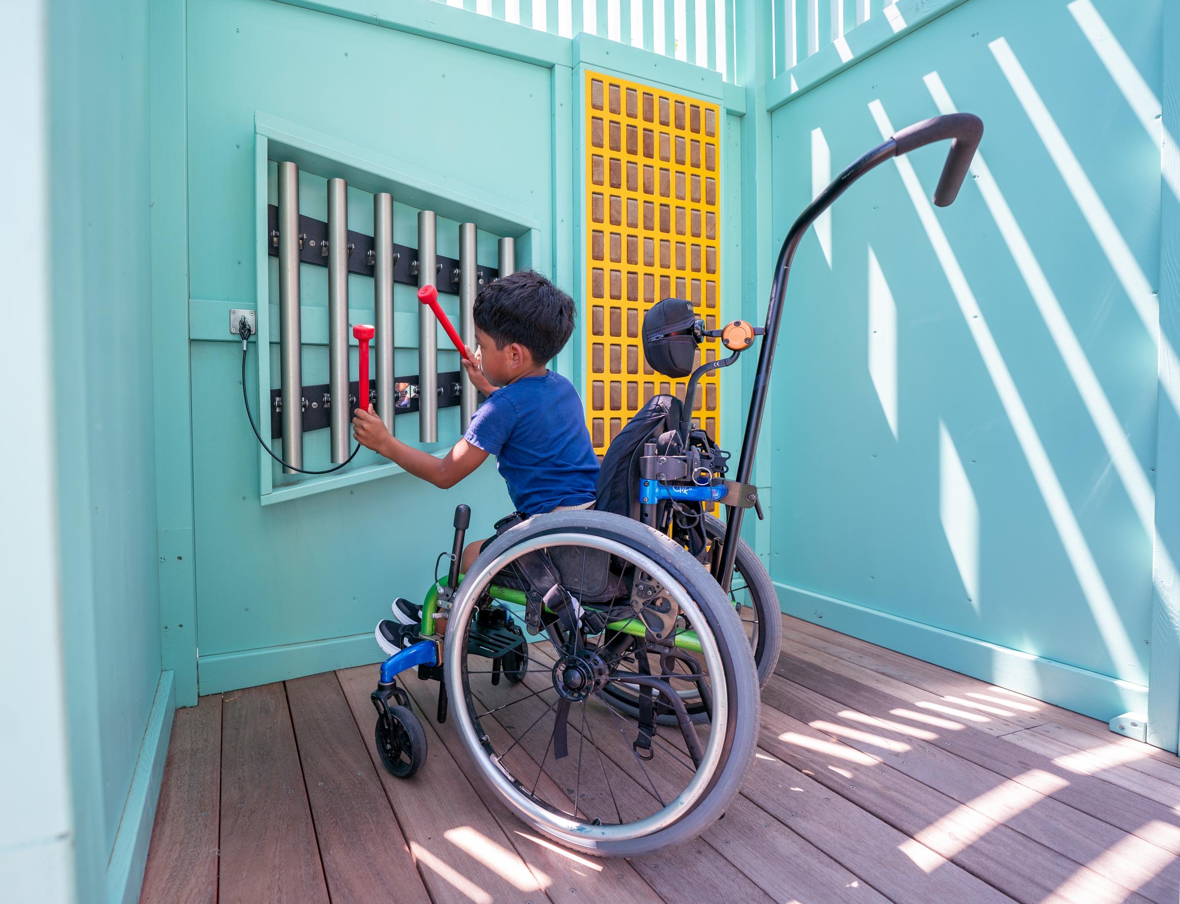 Boy playing on musical play feature at inclusive playground