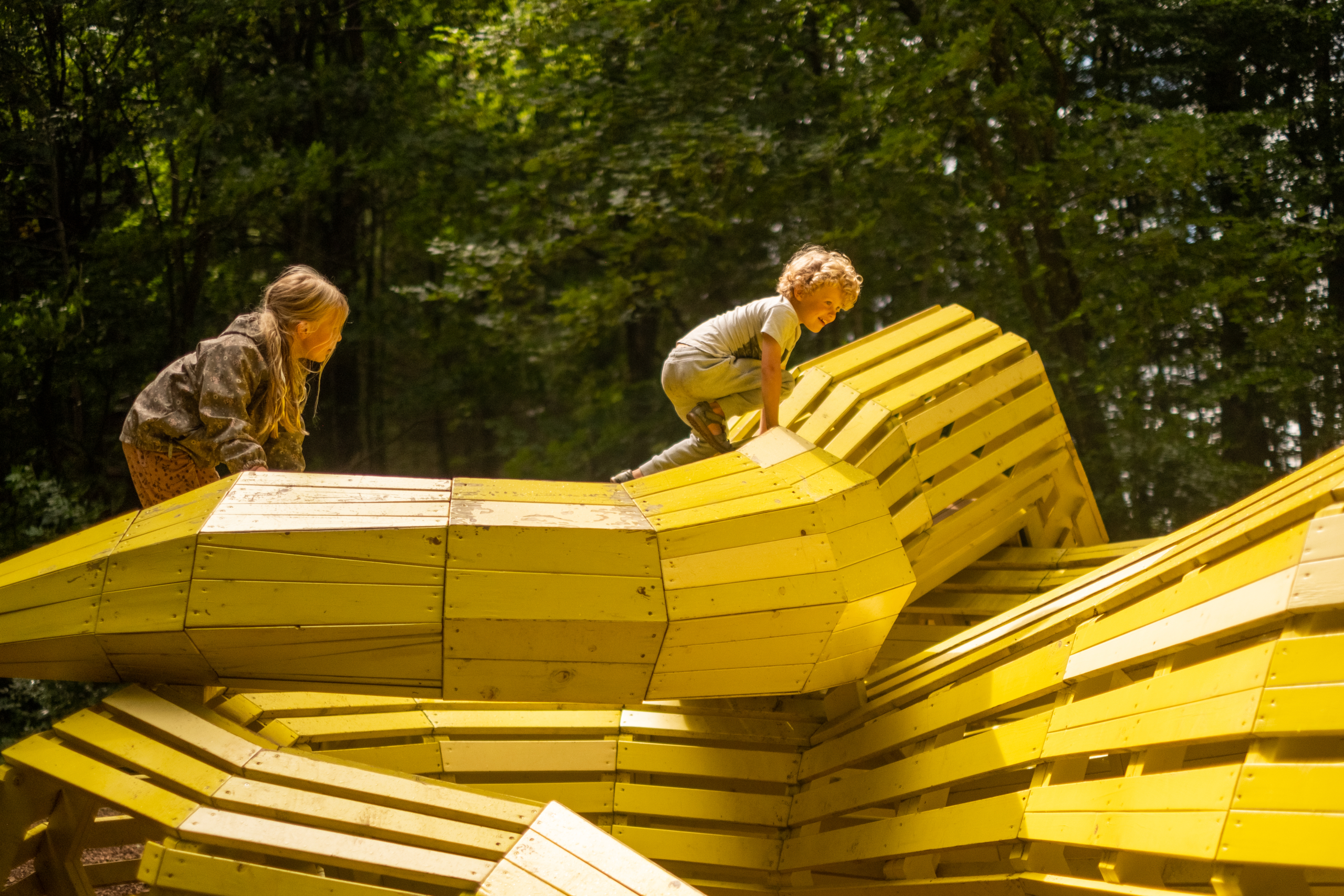 Kids climbing and playing on snake playground sculpture