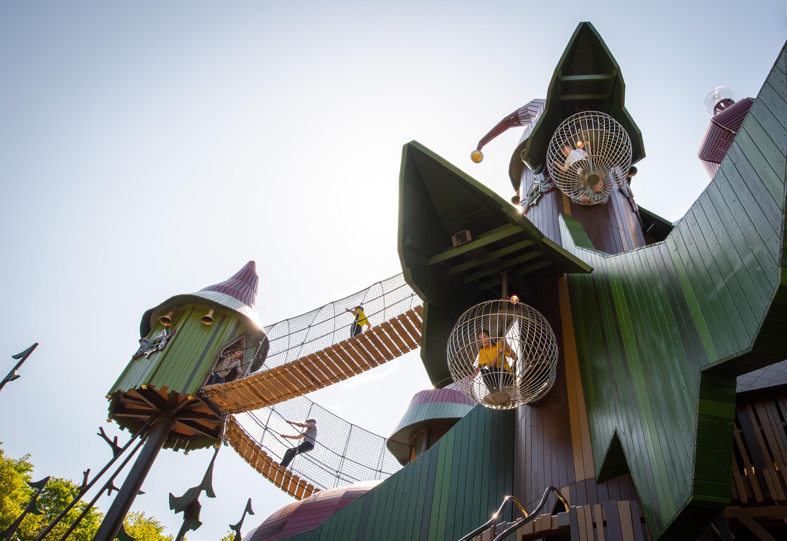 Frog's eye view of children climbing and playing on huge wooden playground structure