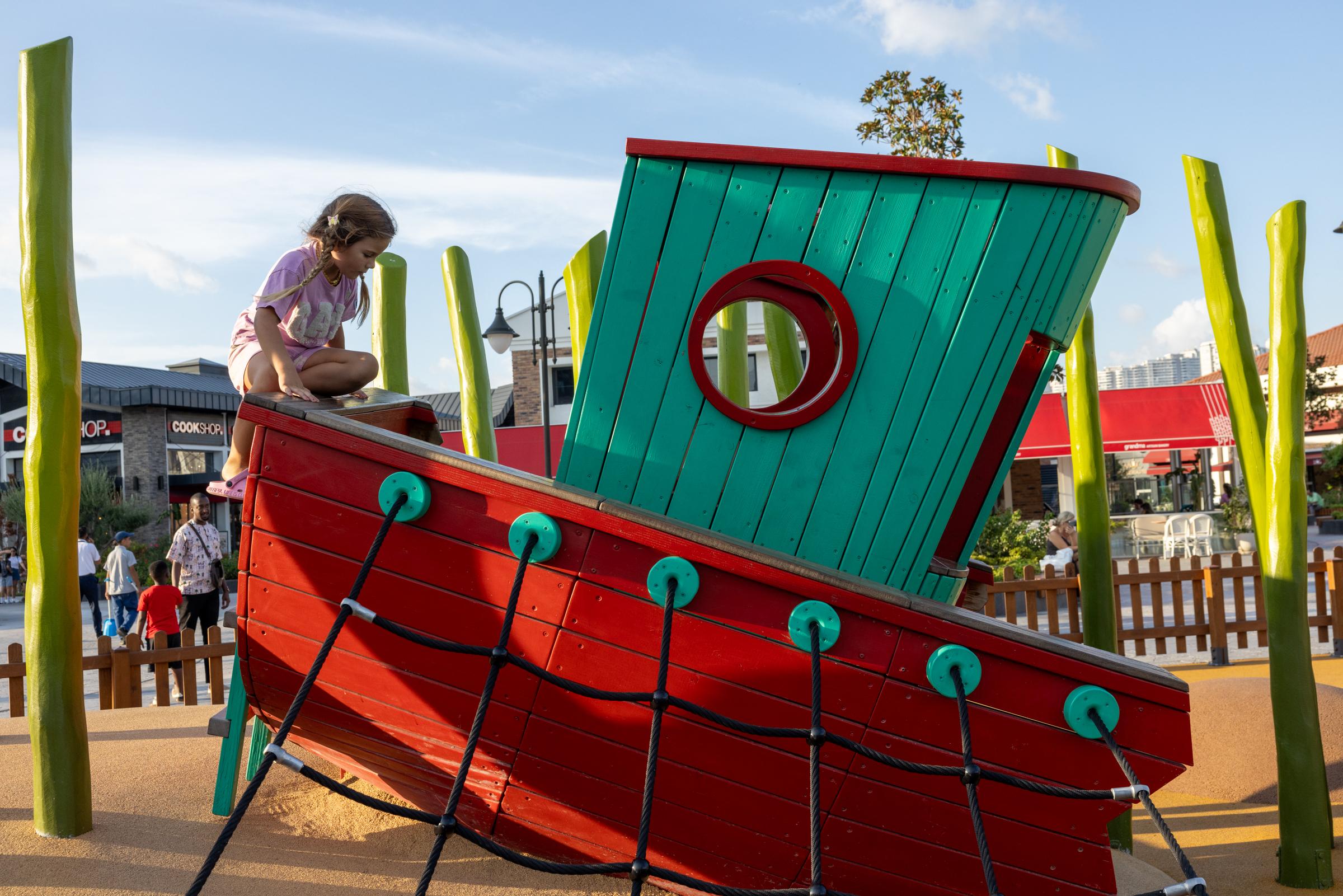 Girl climbing up onto fun playground boat