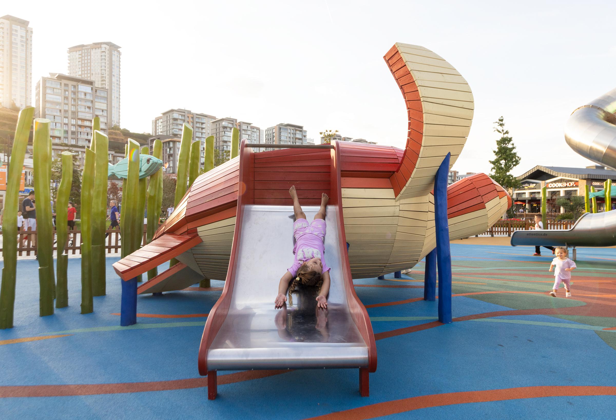Girl sliding down playground slide upside down
