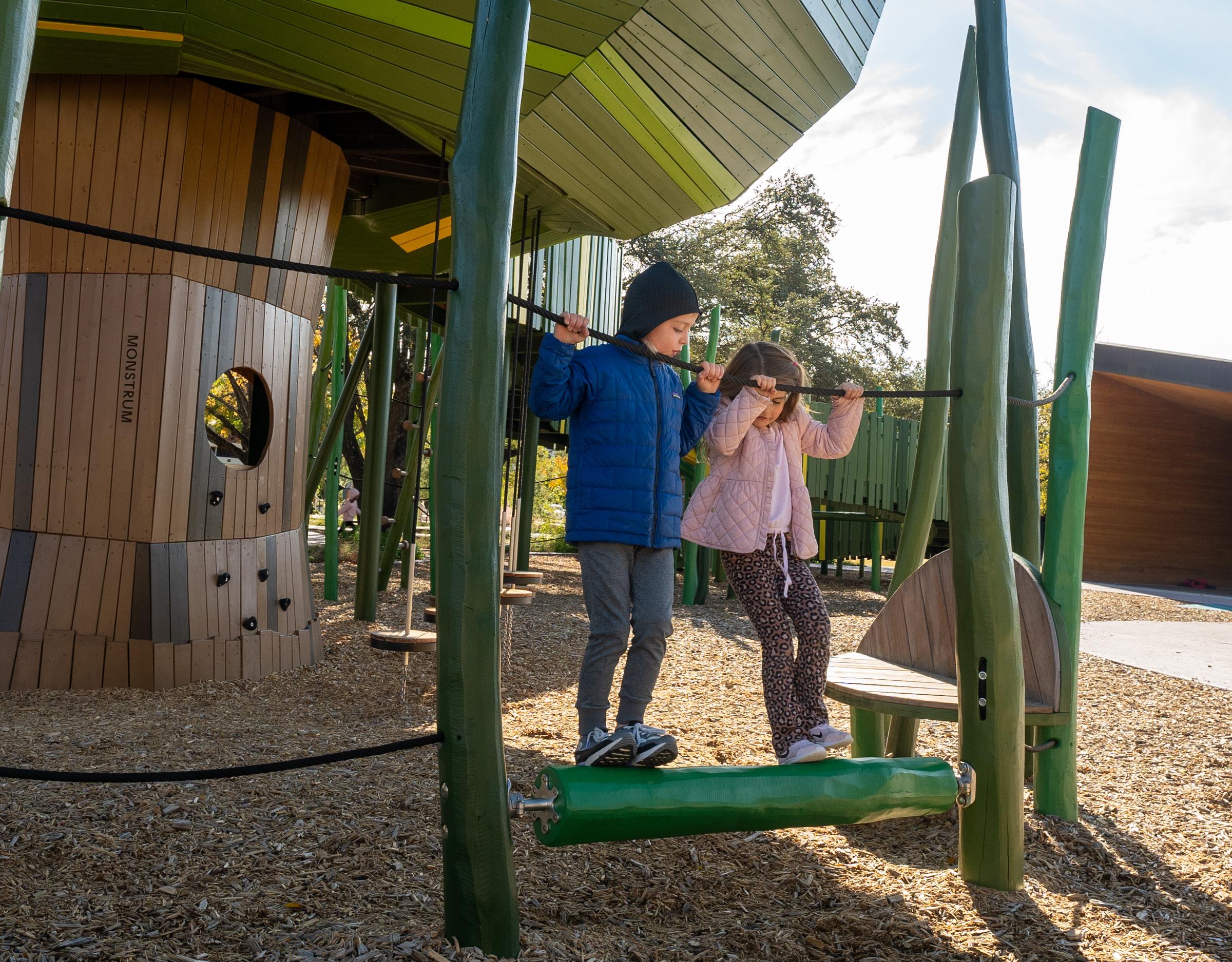 Kids playing on rolling beam playground feature