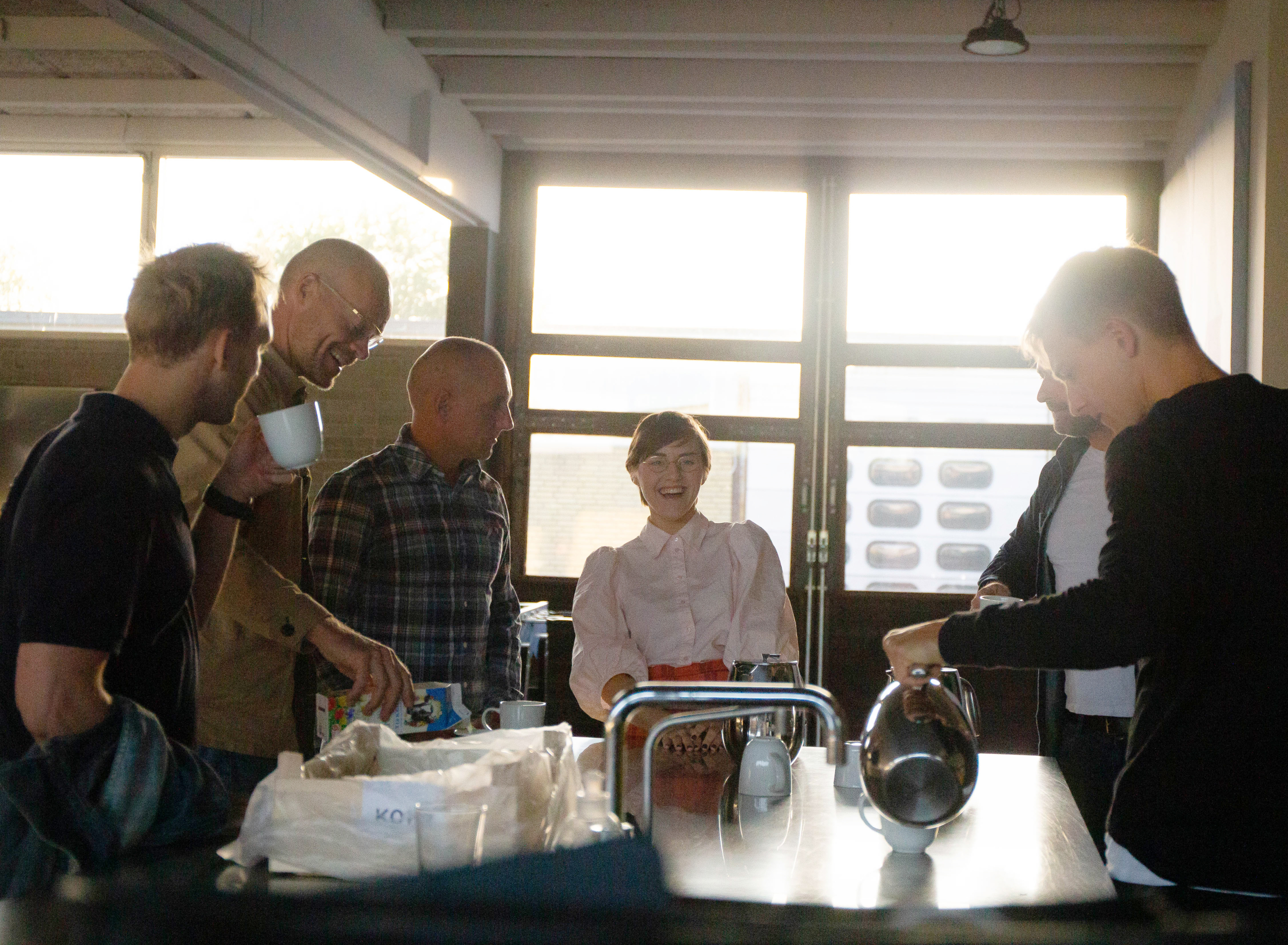 People standing at chatting and laughing over coffee at MONSTRUM Playgrounds offices