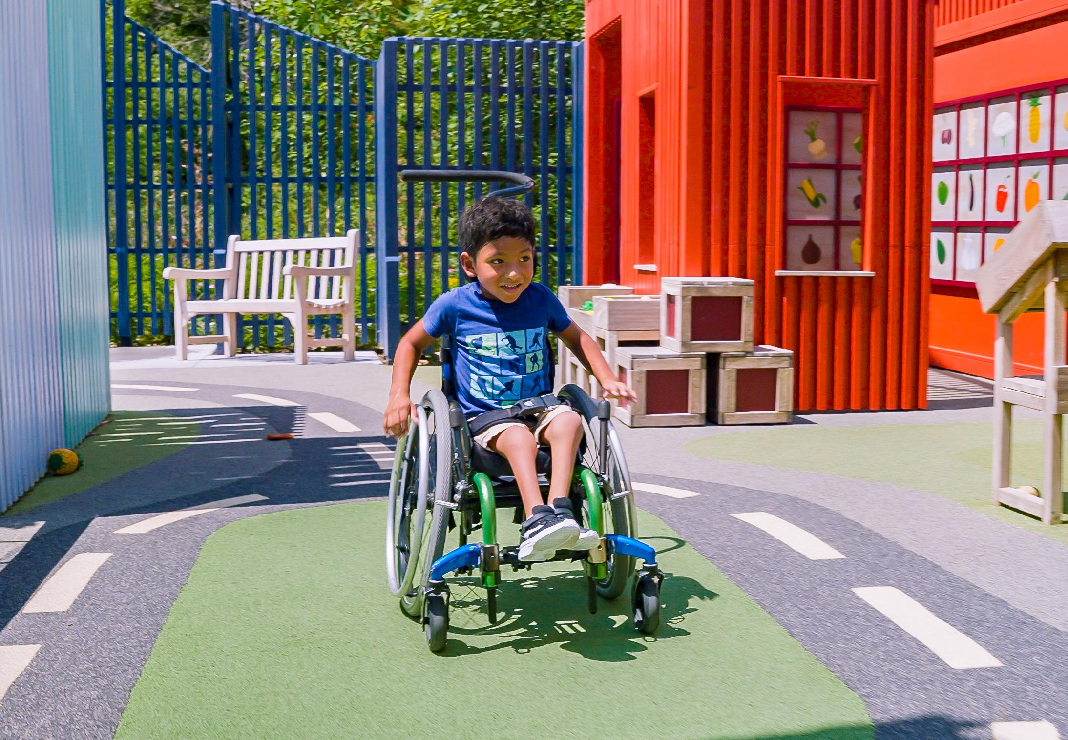 Boy in wheelchair rolling around accessible playground