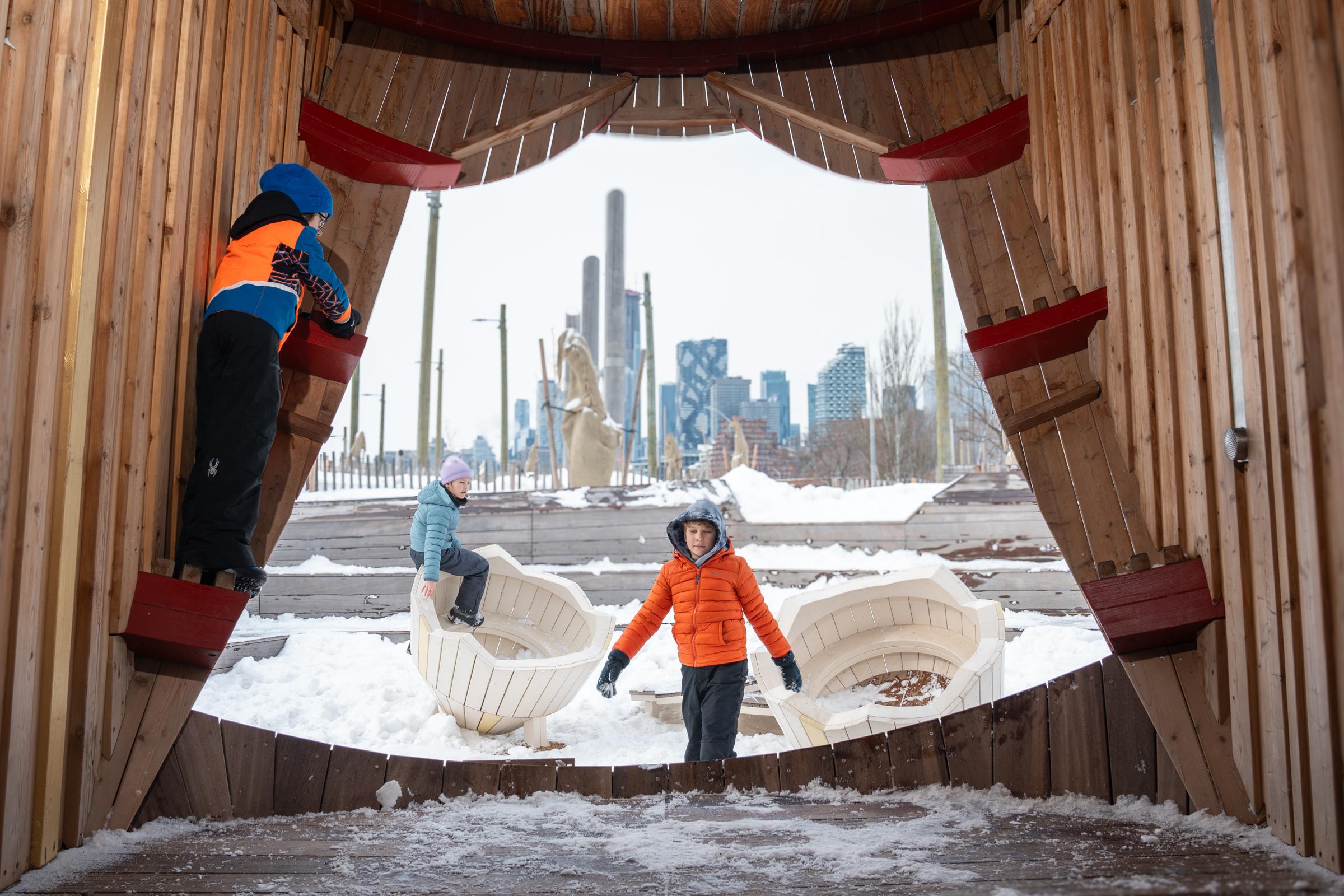Kids playing in the entrance of huge wooden owl sculpture