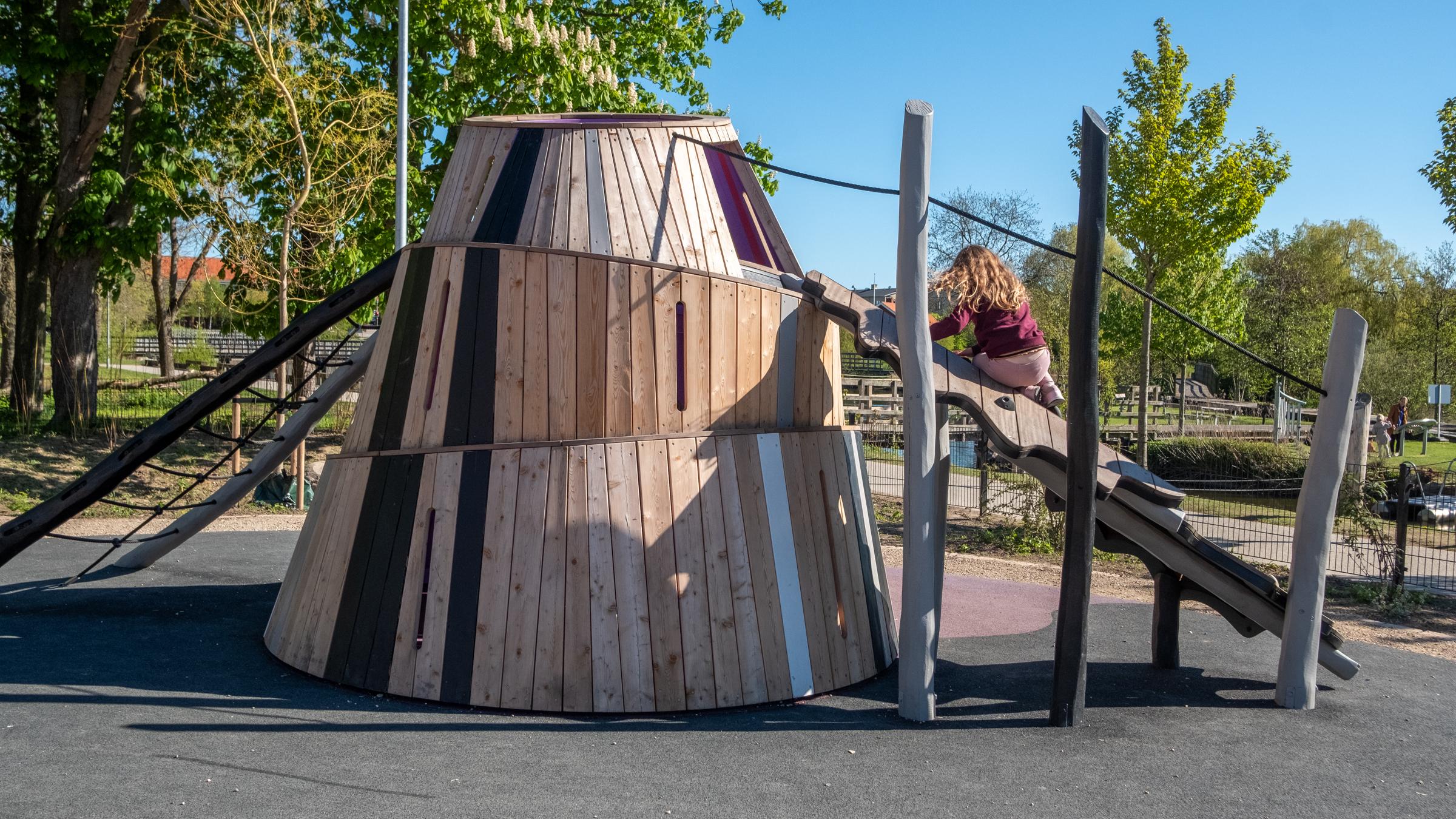 Girl climbing up wooden playground mountain