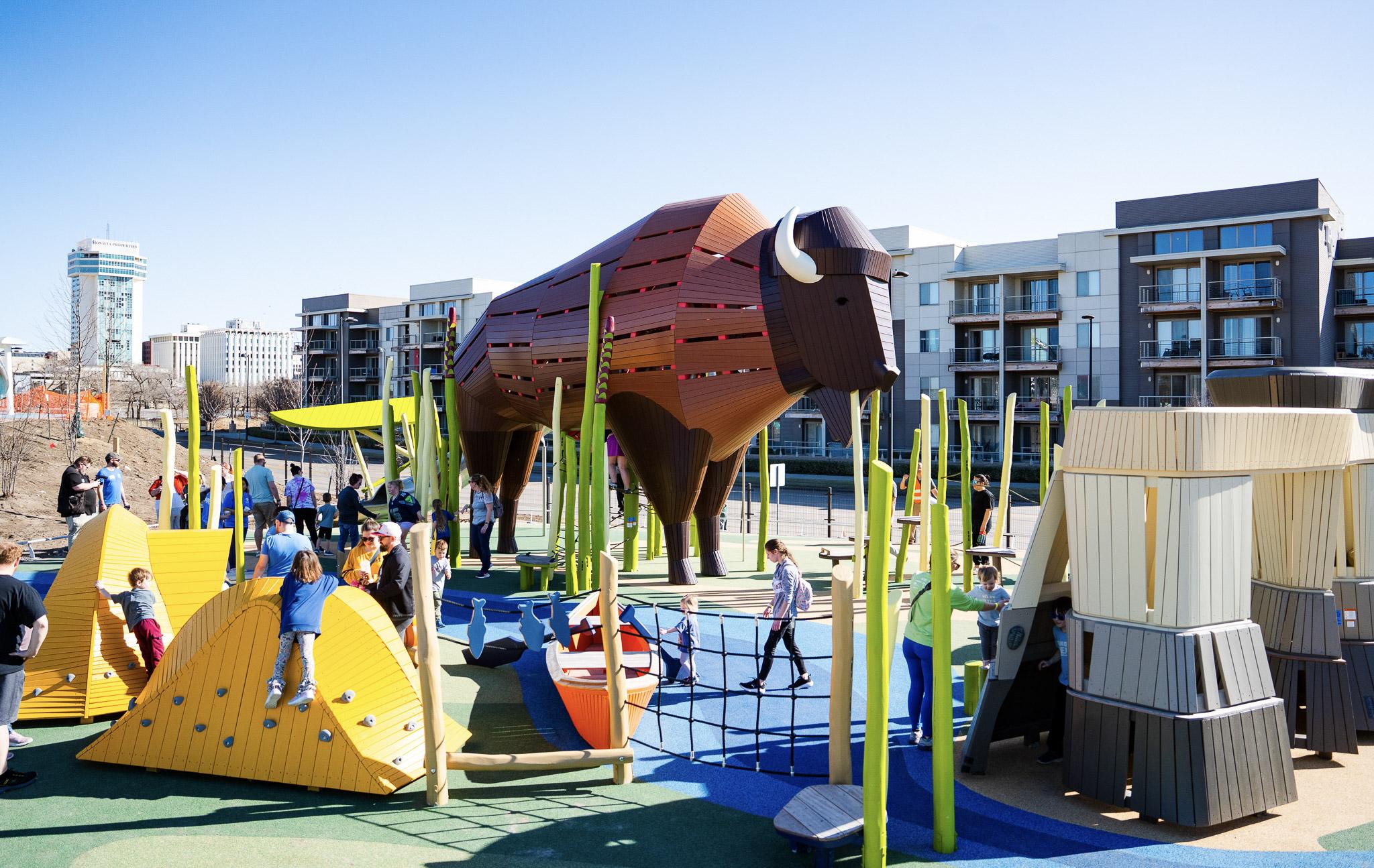Huge wooden bison themed playground with tents, a canoe and a rock formation