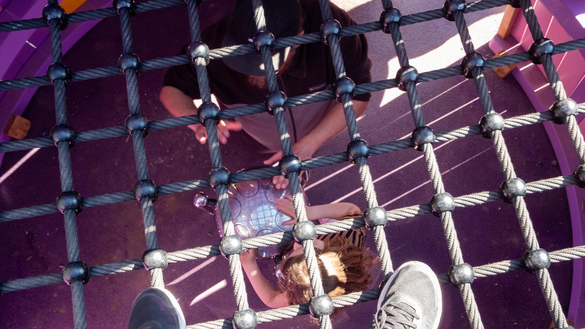 Looking down at girl and her dad playing steel drum at playground
