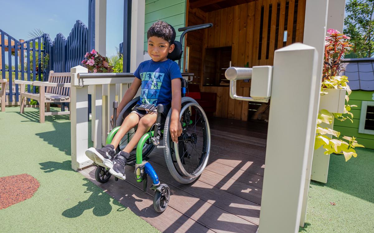 Boy in wheelchair on accessible playground ramp