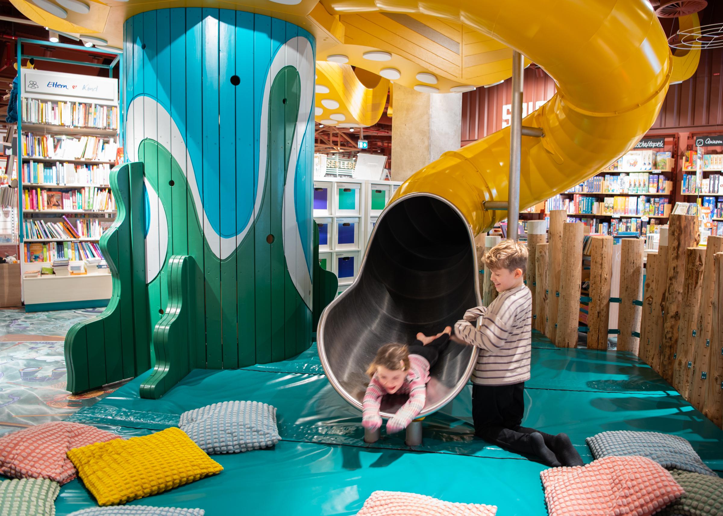 Boy and girl playing and laughing at bottom of octopus tube slide