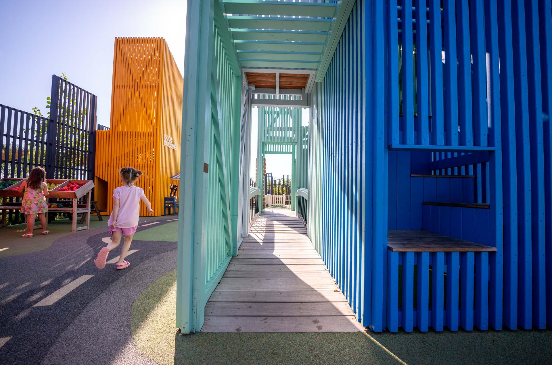 Children running past playground tower with accessible ramp