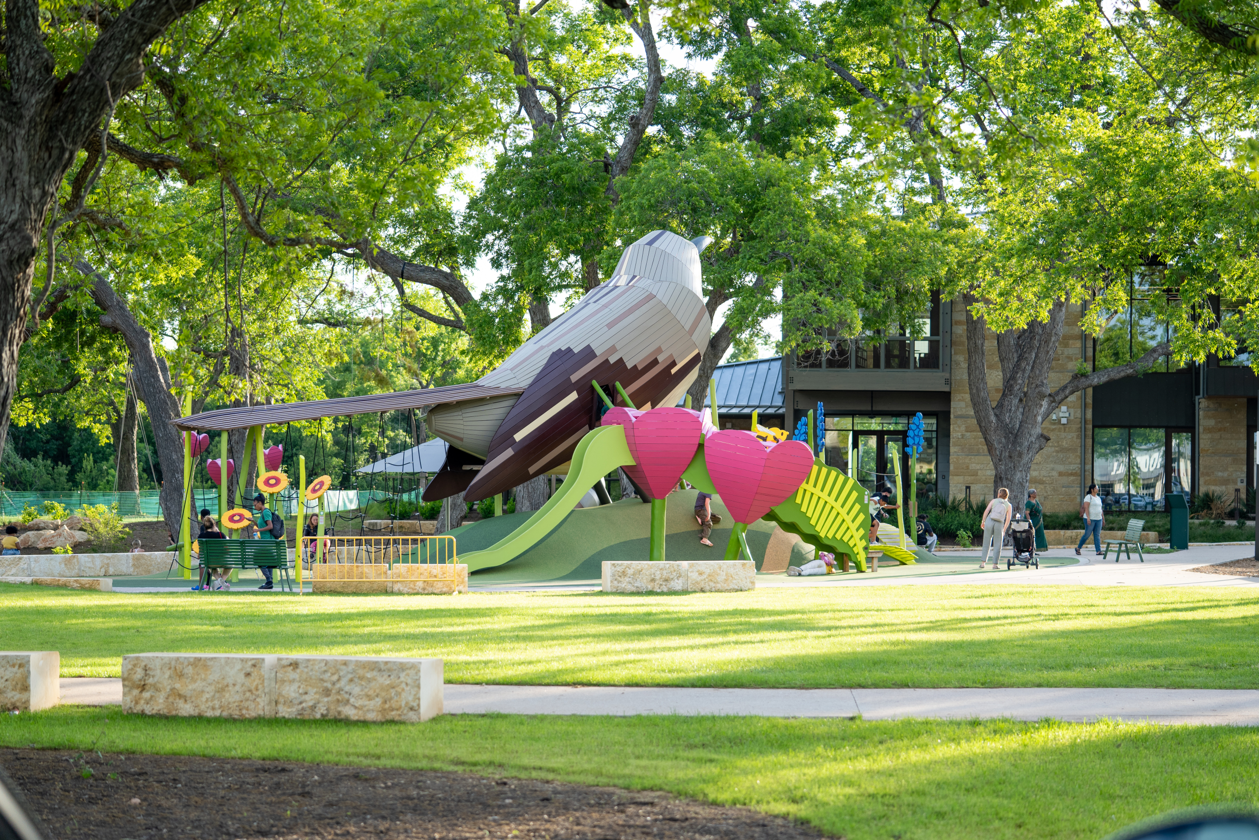 Wide shot of mockingbird wooden playground structure at Cedar Park library