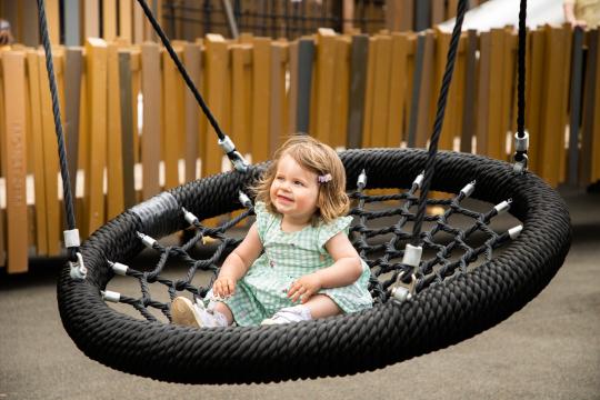 Little girl sitting on basket swing