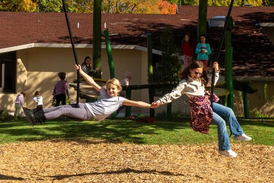 Children having fun on zip slides holding hands