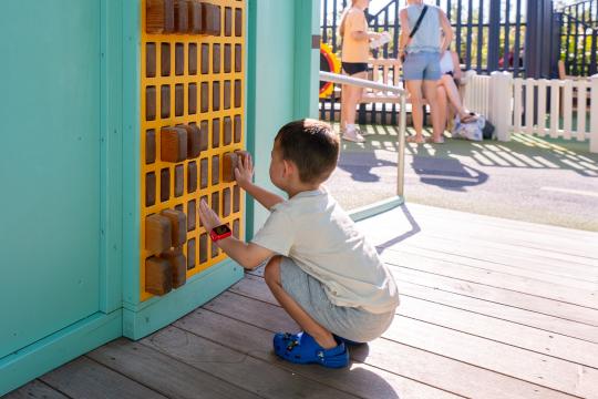 Boy playing with sensory pin board play feature at playground
