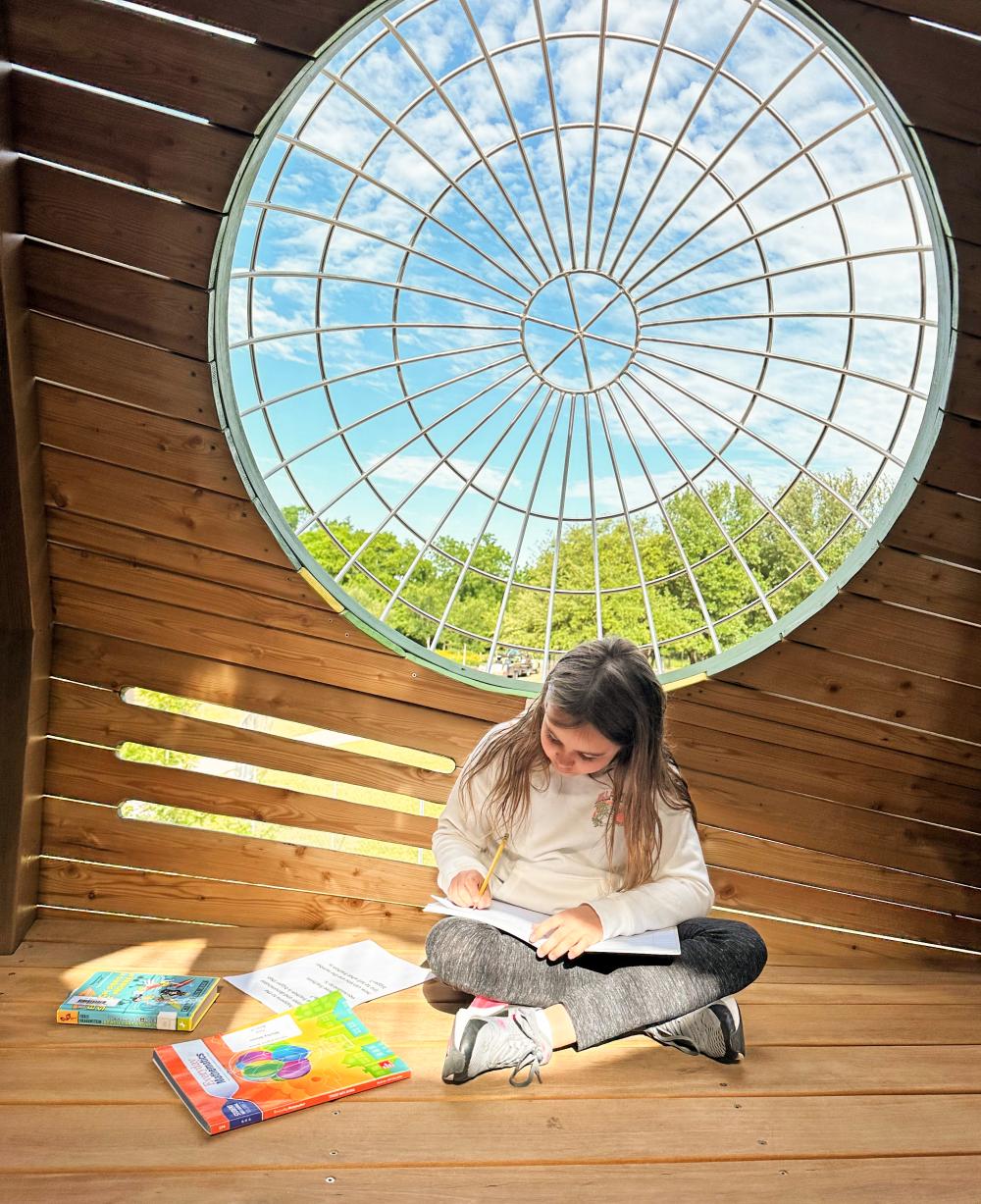 Girl doing her homework inside huge wooden tree structure