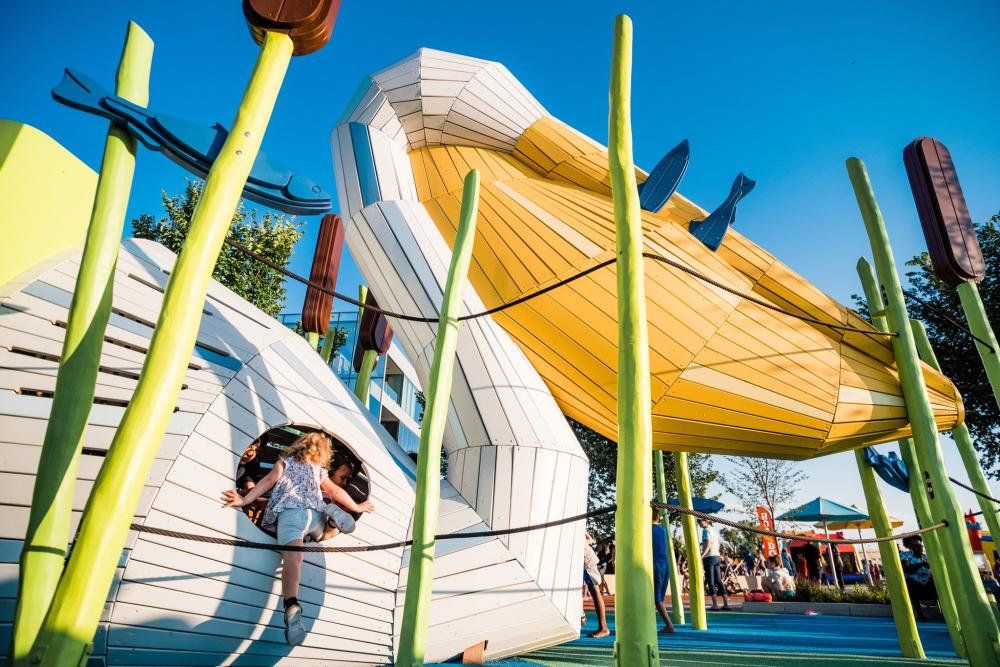 Girl climbing into wooden pelican playground structure